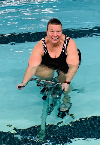 Lisa H. wearing JunoActive swimwear working out on bike while in a pool