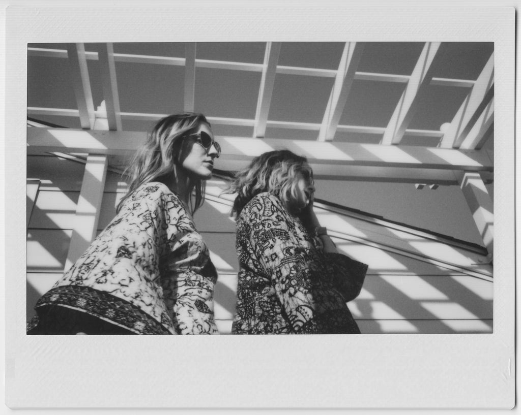 polaroid profile of models in robes on a balcony.
