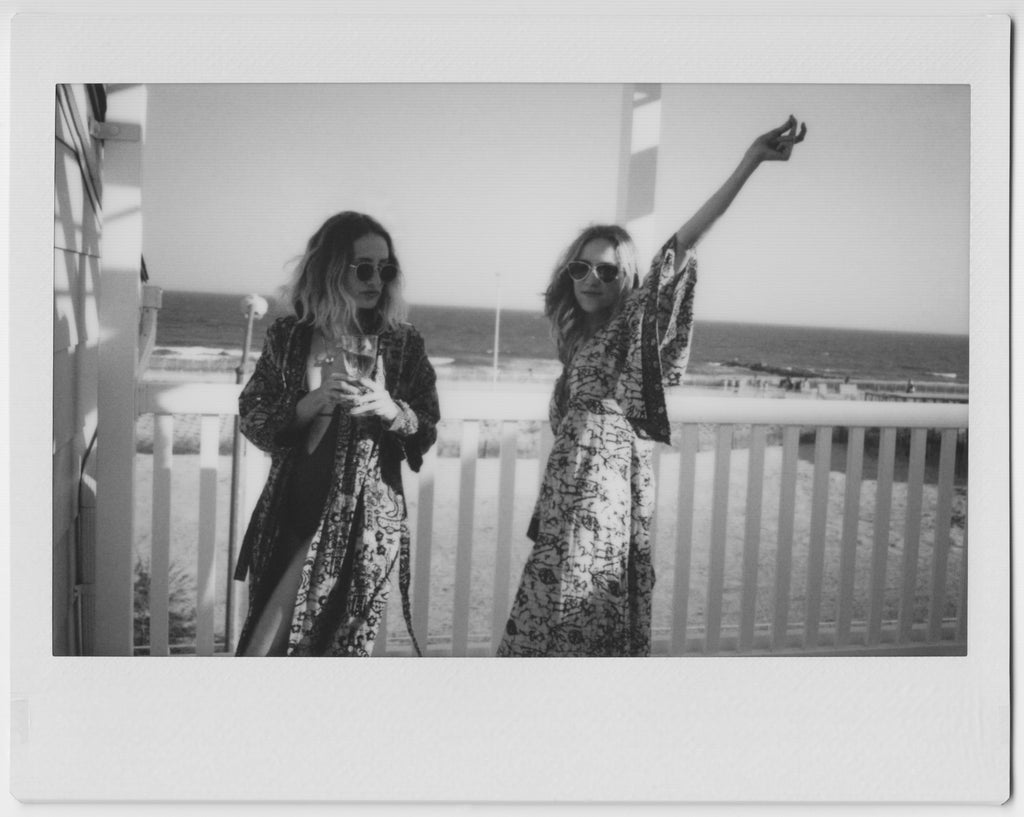 models on balcony overlooking rockaways in swim wear and robes and sunglasses.