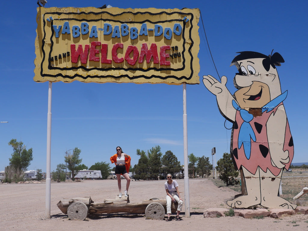 people standing next to sign that says welcome to the flinstones campground.