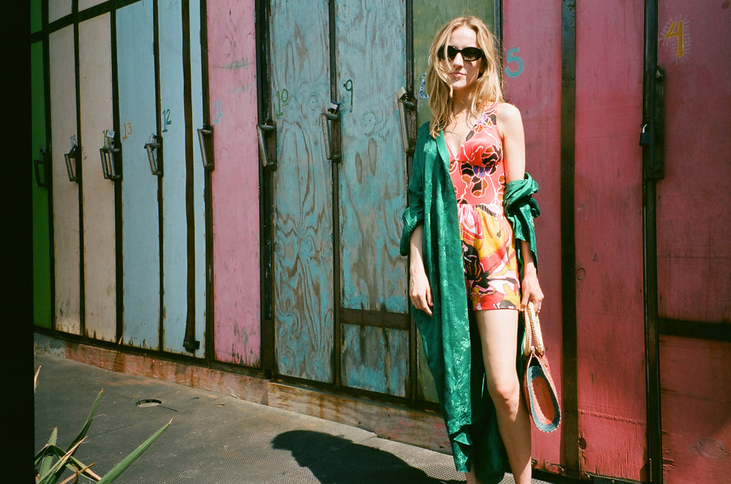 model in mixed prints and a silk robe in front of surf board lockers.