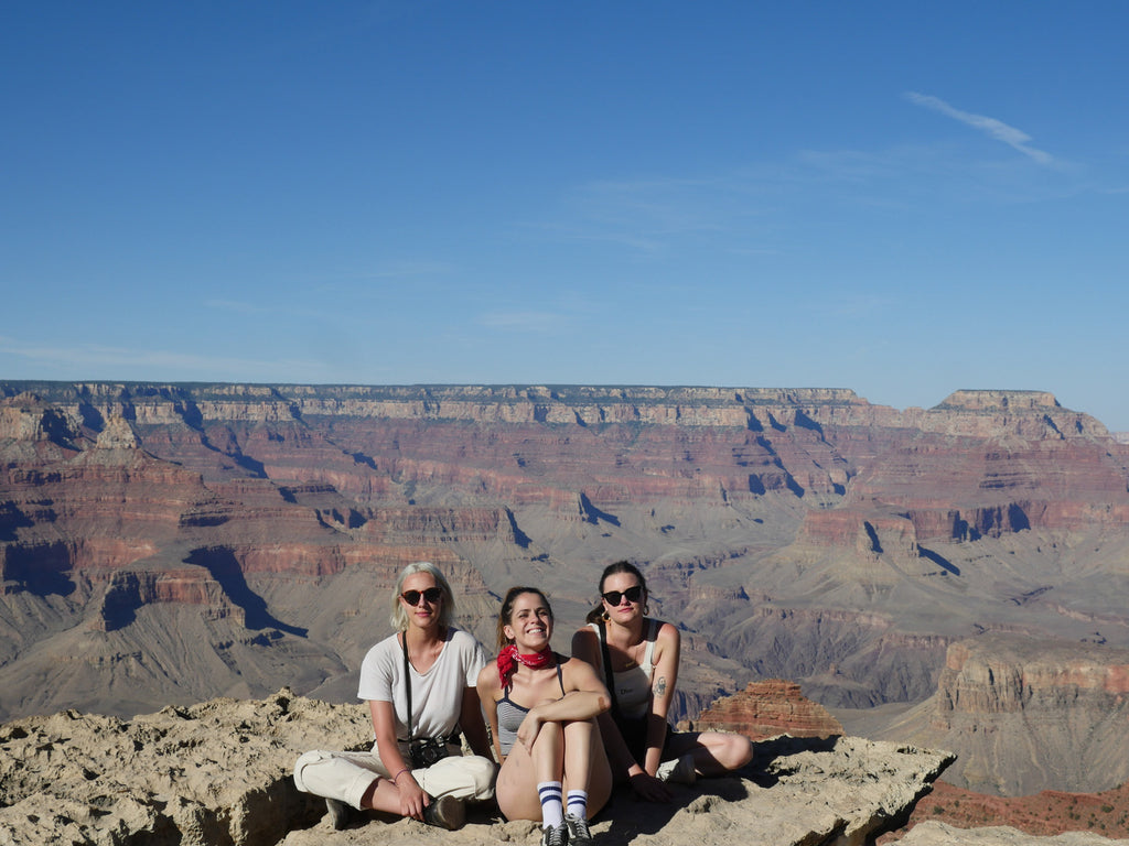 three people sitting on the edge of a cliff.