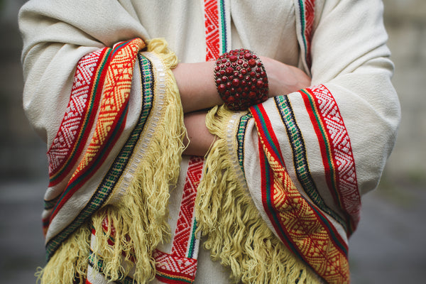 detail of arms crossed in folk inspired dress with cuff bracelet.