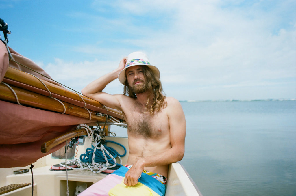 model seated and leaning on sail of sailboat.