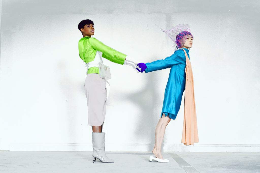 two models posing in abstract head pieces and holding hands.