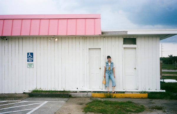 a person standing in front of a white and pink building.