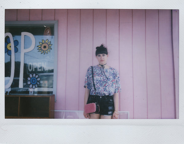 a person is standing in front of a pink building.