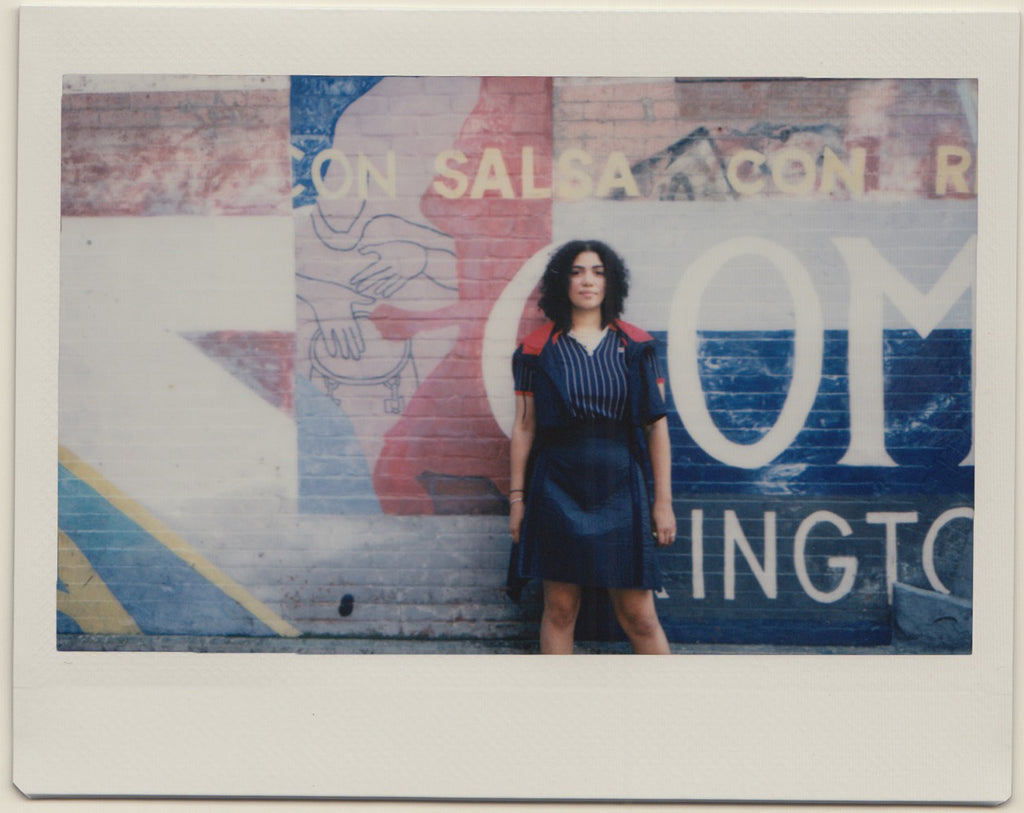 paola in front of painted brick wall.