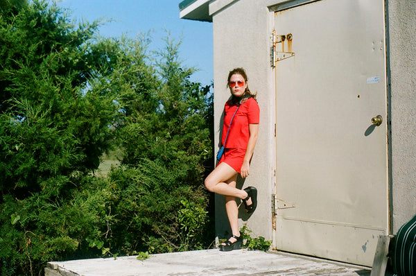 a person in a red dress leaning against a wall.