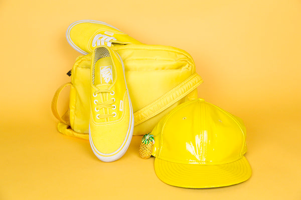 tonal still life of sneakers, bag, cap and brooch.