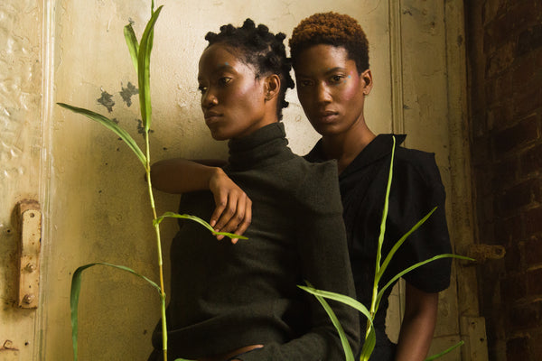 twin models posing together featuring a stalk of grass each.