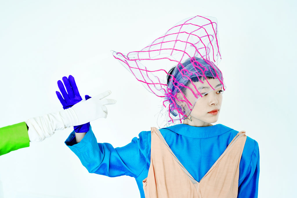 abstract shot of model with cool head piece and another models hand.