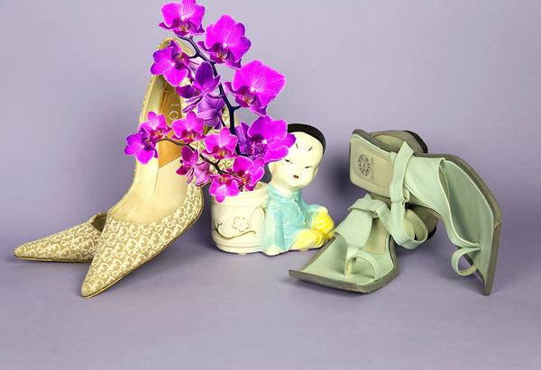 still life of dior pumps and sandals and orchids.