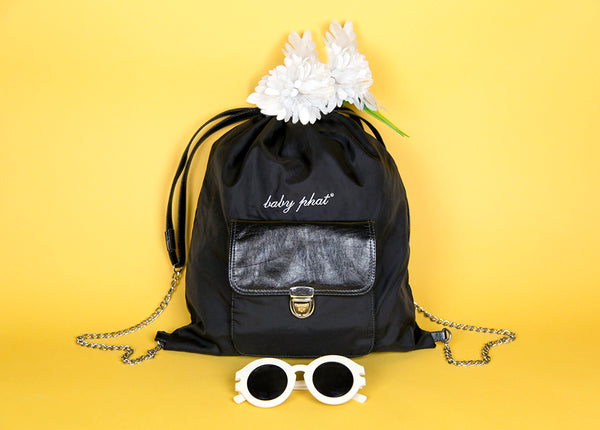 still life of baby phat backpack, sunglasses and flowers.