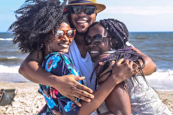 Friends man and two women hugging and smiling  on beach