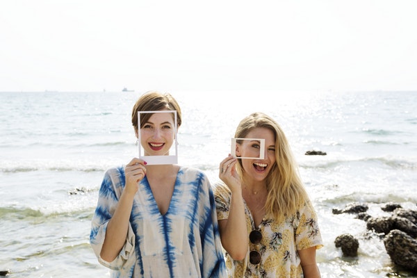 Friends in fun Polaroid frames smiling at seaside
