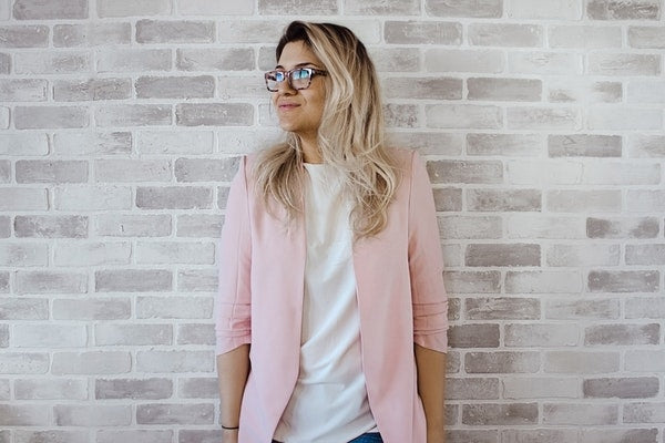 Blond woman with glasses in pink blazer smiling