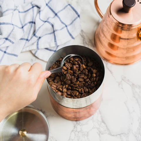 coffee being scooped out of a copper canister