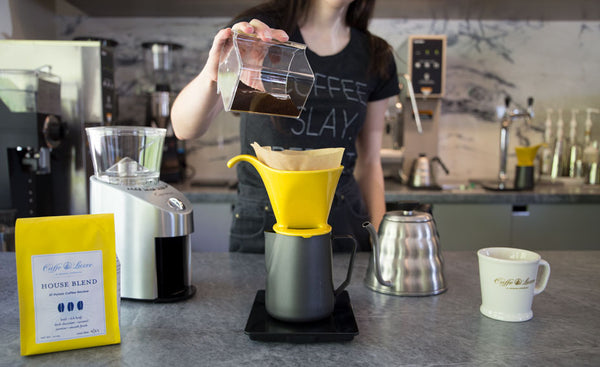 a woman dosing coffee into pour over