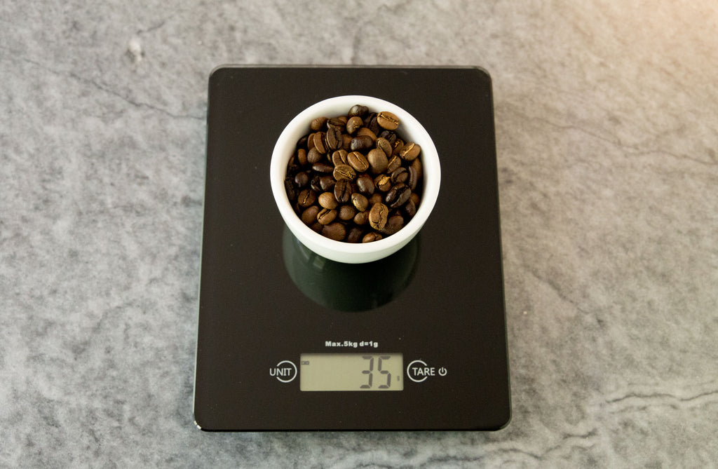 35 grams of coffee weighed out in a white cup on a black scale