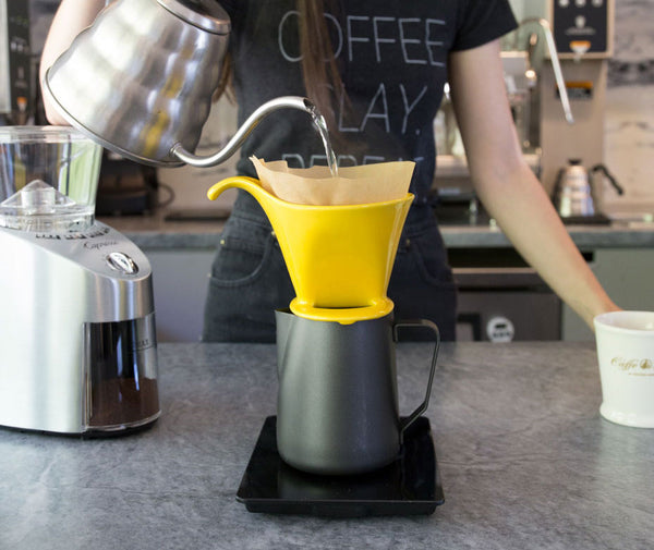 a woman pouring water into pourover