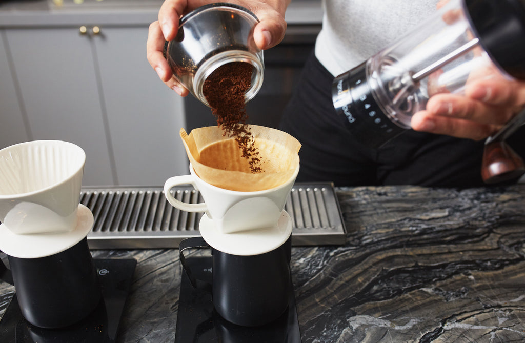 a person adding coffee to kalita 102 dripper