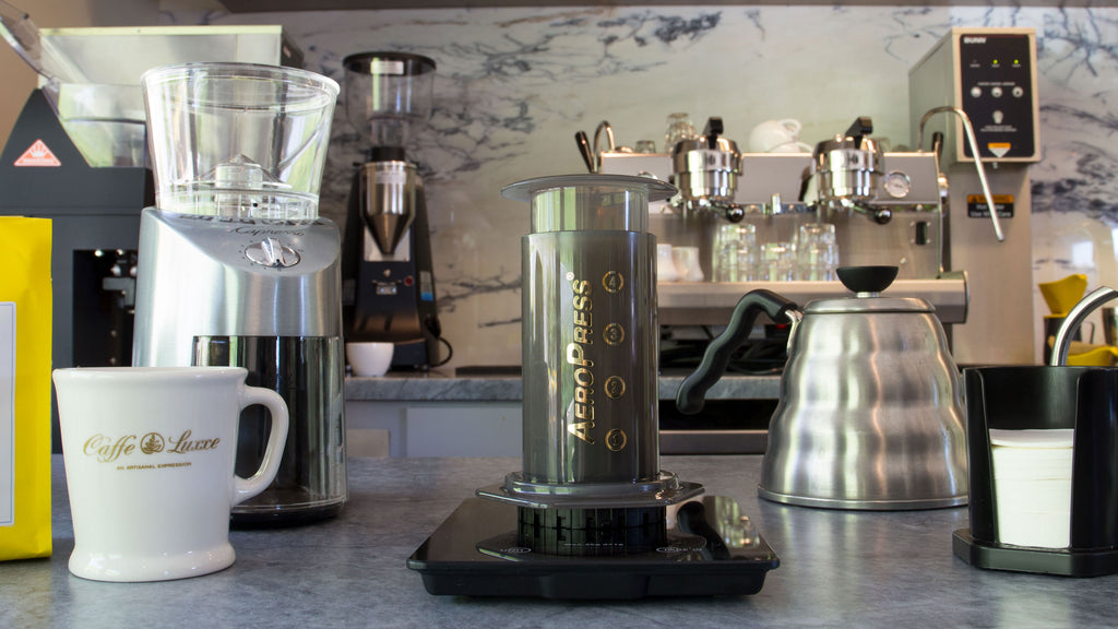 aeropress coffee maker displayed in the center with various brewing equipment at its sides