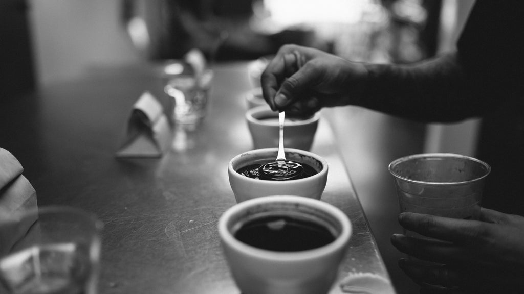 a black & white photo of a person putting a spoon into a cupping bowl