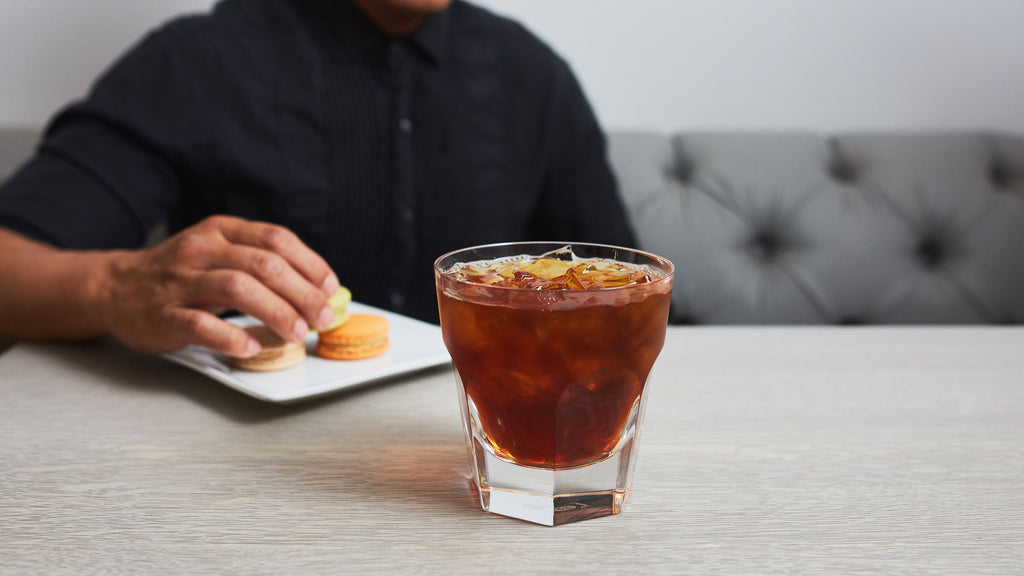 iced coffee in small glass in front of a seated man