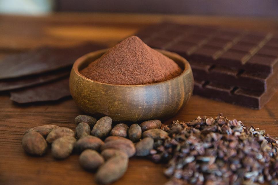 cacao powder in a bowl with cacao nuts and chocolate bars