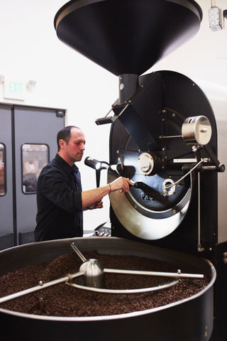 a man roasting coffee on a probat coffee roaster