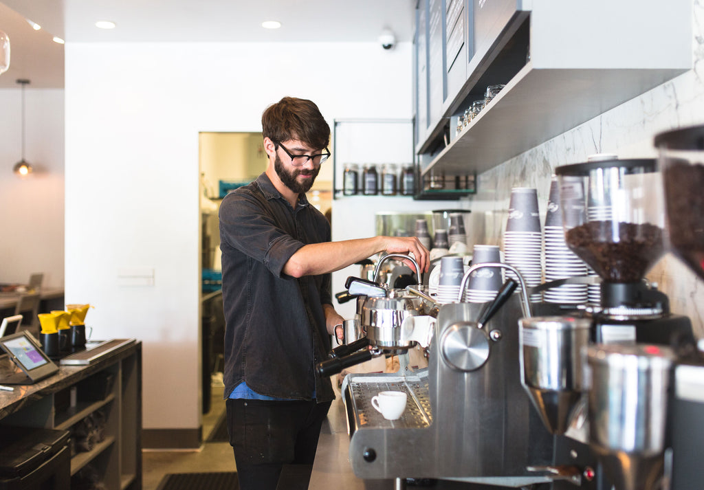 a man smiling while making espresso