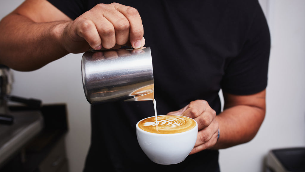 a person in a black shirt pouring latte art