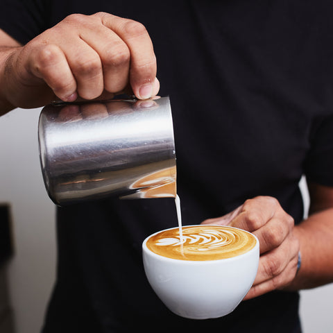 a person in a black shirt pouring latte art