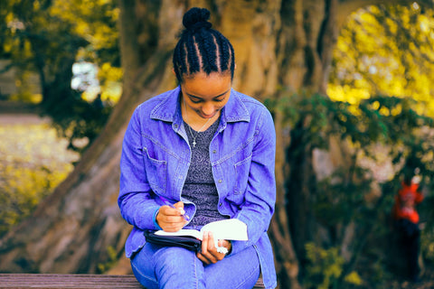 Photo by Gift Habeshaw on Unsplash Black woman with braided hair reading a book outside