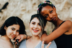 Three women with arms resting on shoulders. Photo by Omar Lopez on Unsplash