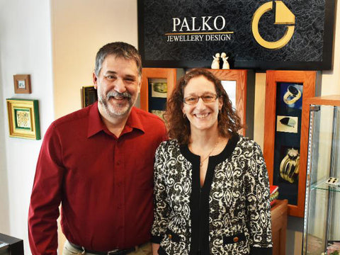 Chris and Carol Palko, happy husband and wife team of Palko Jewellery Design.  Smiling and standing in their showroom, arm in arm.