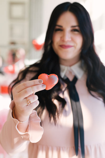 Sarah holding up one of the heart macaron pastries at her Galentine's Brunch hosted by Sarah Tripp of Sassy Red Lipstick at Le Marais Bakery in San Francisco