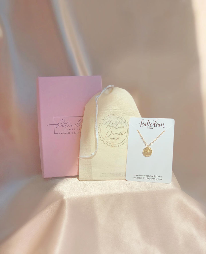 Katie Dean Jewelry larg pink box, canvas bag and necklace card with rainbow necklace displayed