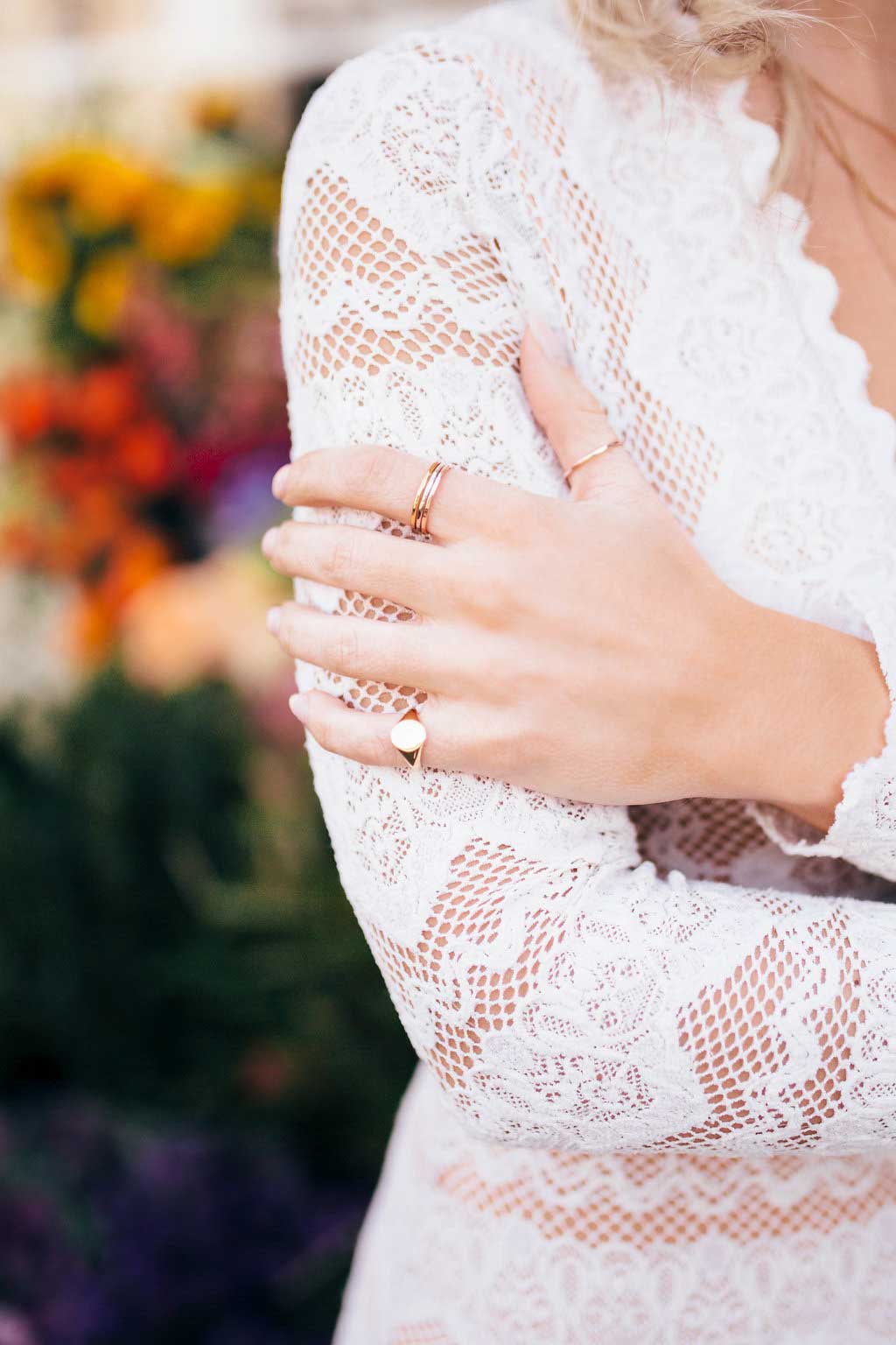 Woman wearing white lace shirt with hand on arm wearing Katie Dean Jewelry Oval Signat Ring