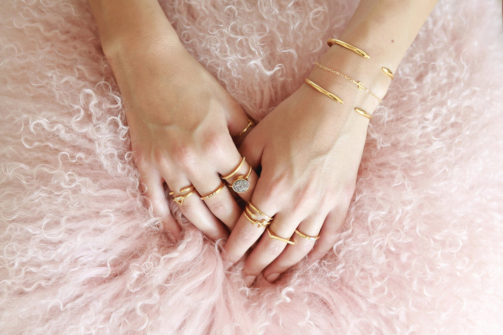 Two hands resting on pink tutu with rings and bracelets.