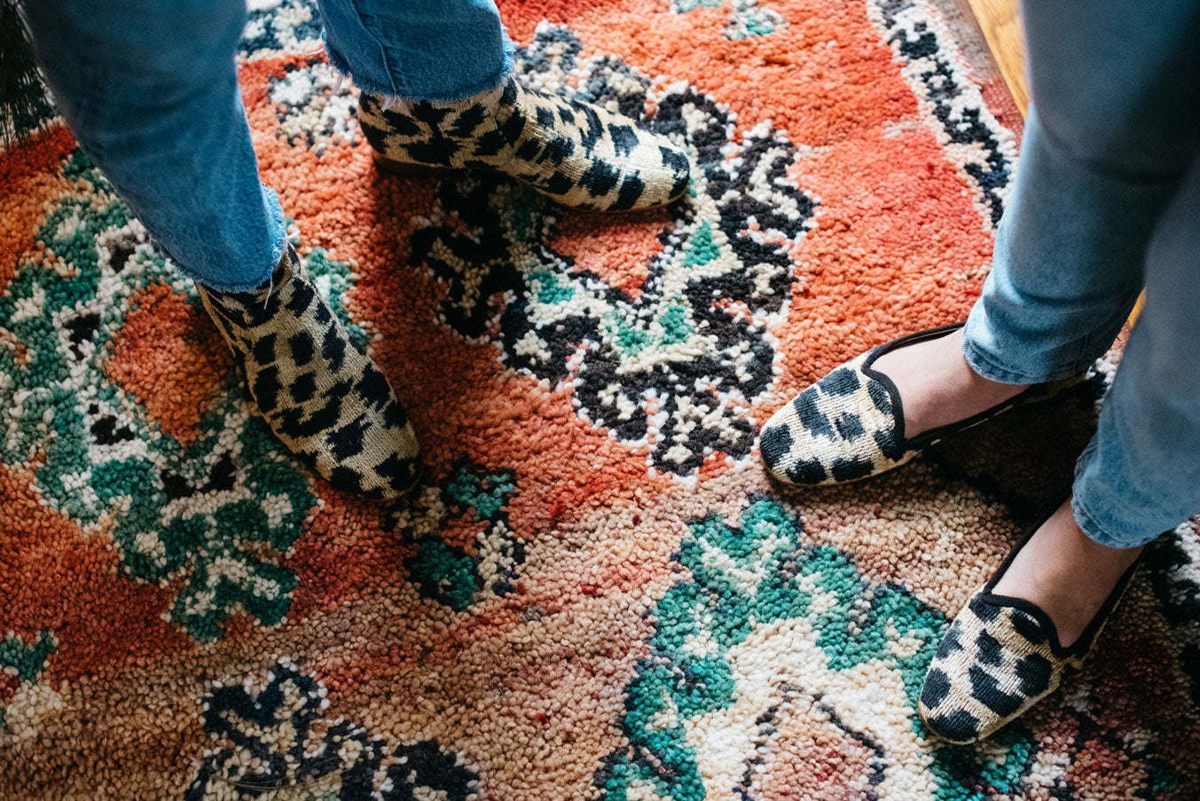 Our leopard print loafers worn on a moroccan carpet next to our matching velvet boots.