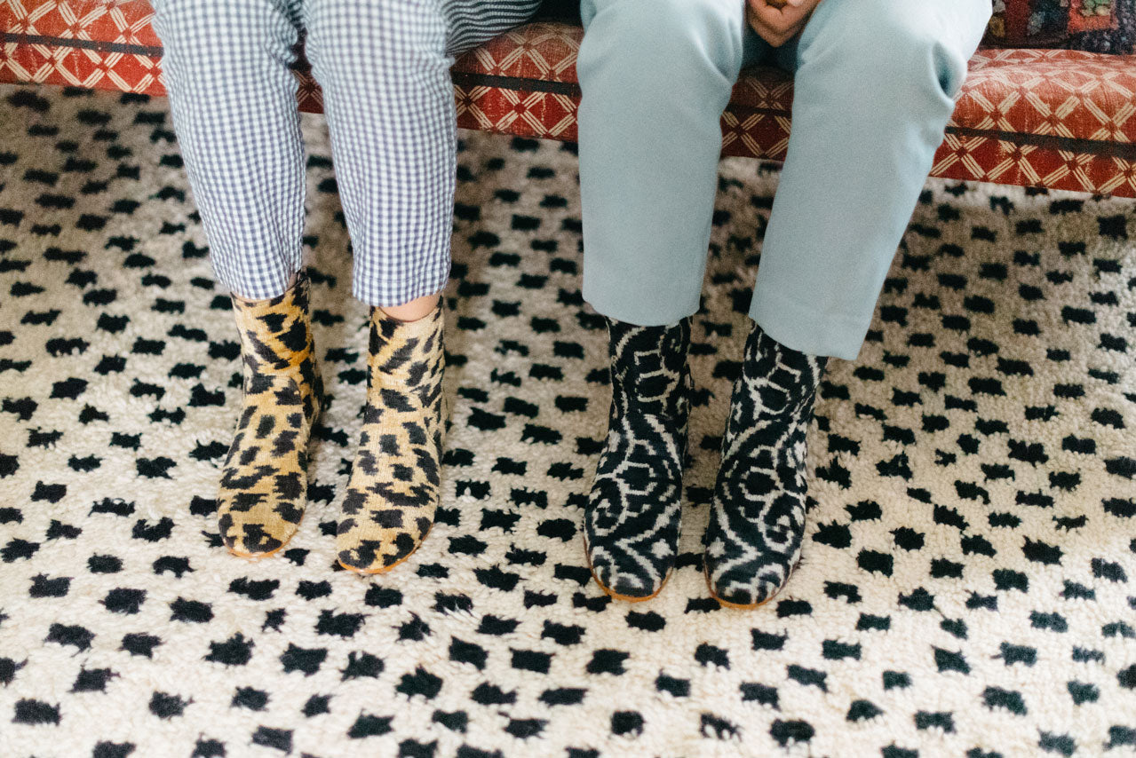 Our leopard print and black and white velvet boots on a moroccan carpet, worn by our designer and her sister in her home.