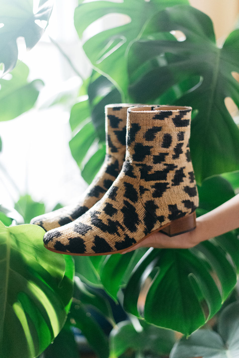 Our velvet leopard print boot photographed in front of a large plant in the designer's home.