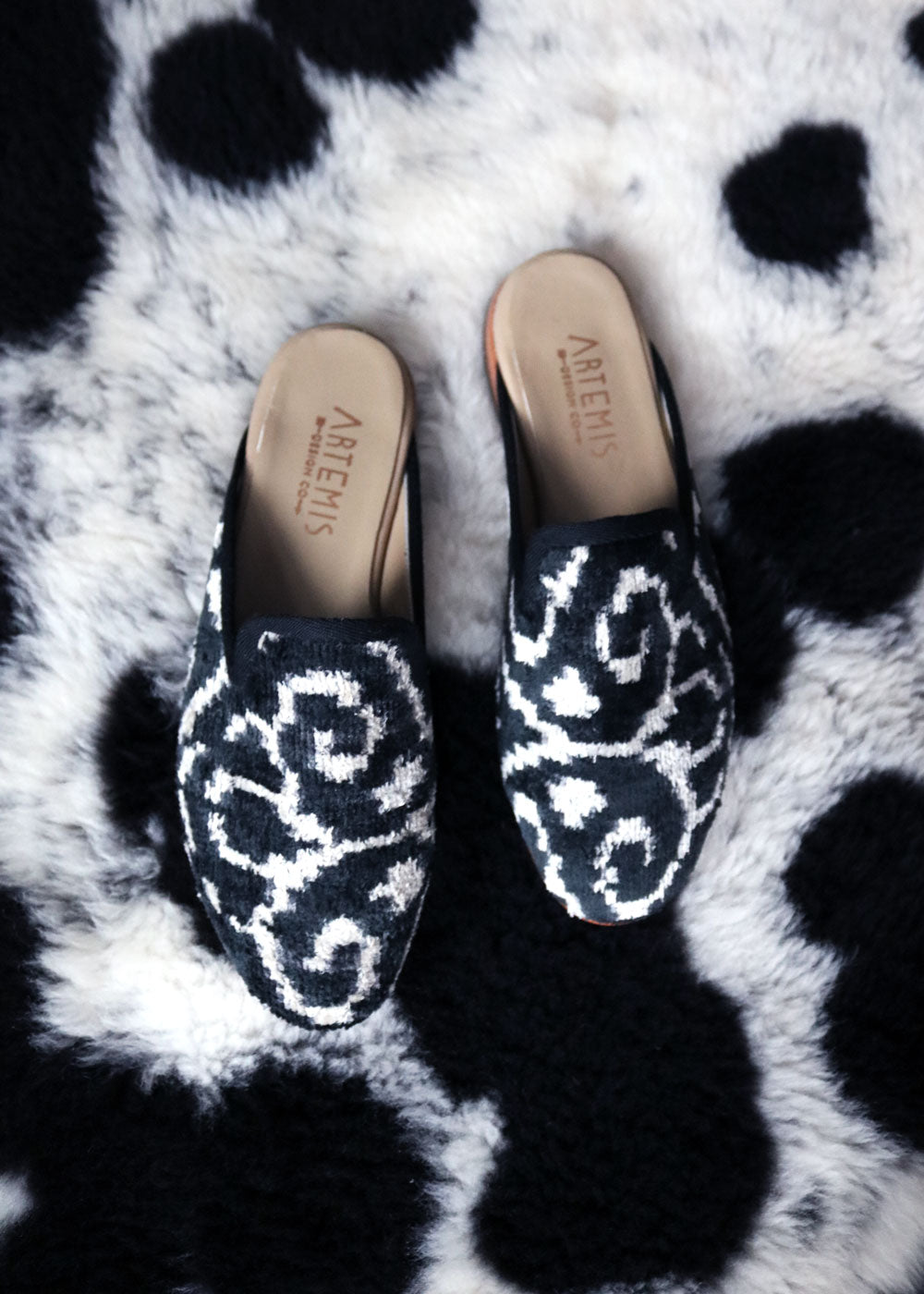 Our black and white velvet slippers on a cow hide. 