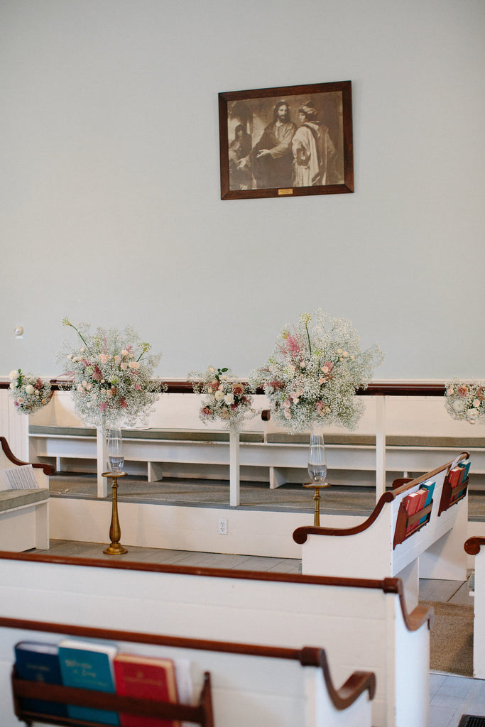 Interior photo of the church. Bouquets of roses and babies breath decorate the church.