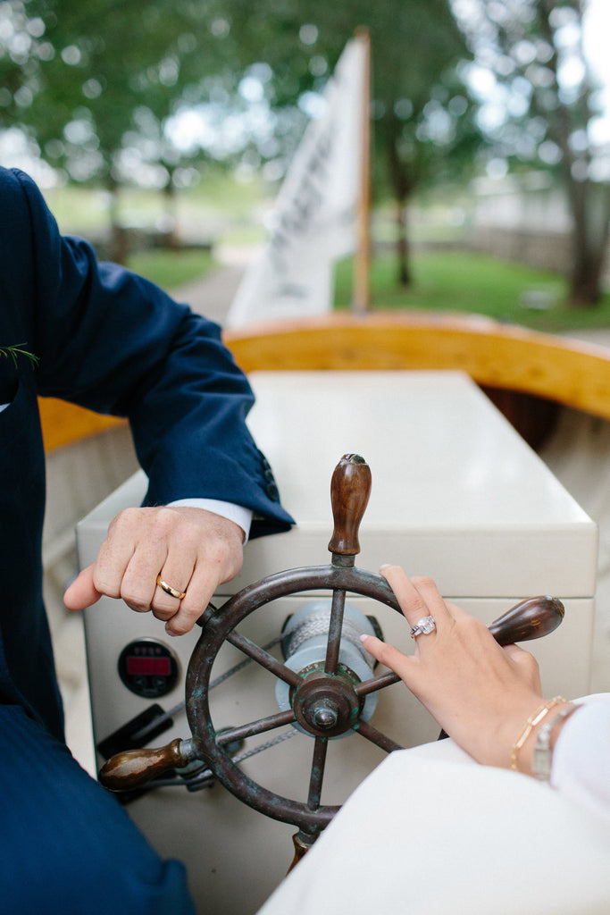 portrait of the newly weds rings on the steering wheel of the vintage boat.