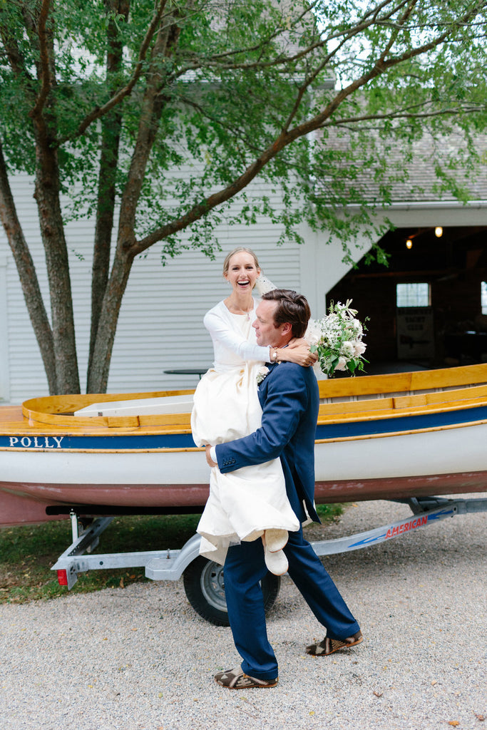 groom carrying the bride out of the vintage boat they arrived in.