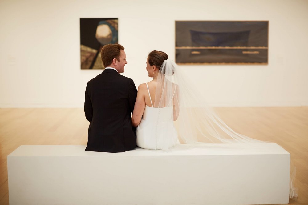 Bride and Groom siting looking at art 