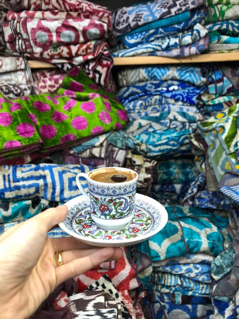 Teacup held in front of assorted colors of velvets in Istanbul.